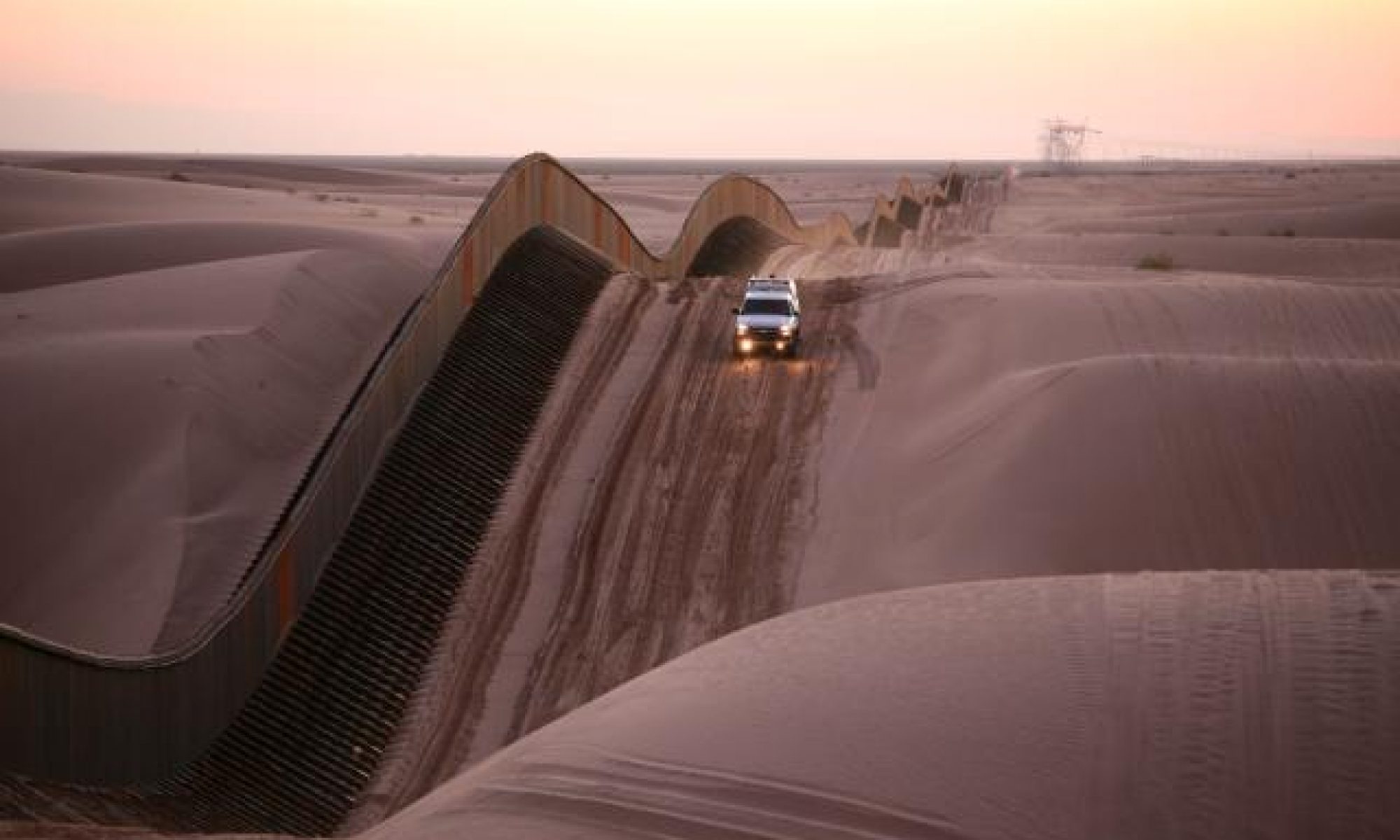 An image of a white truck driving down a sand dune