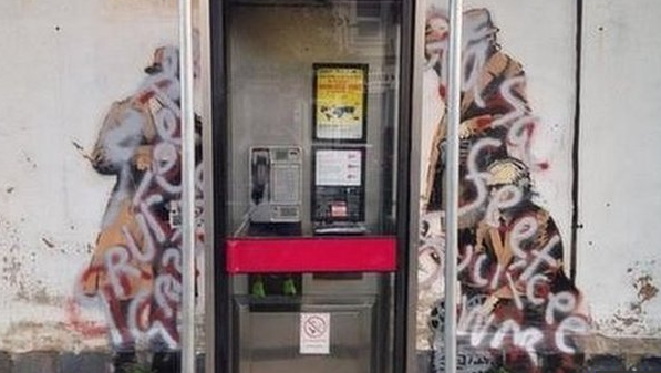 a phone booth with graffiti next to it