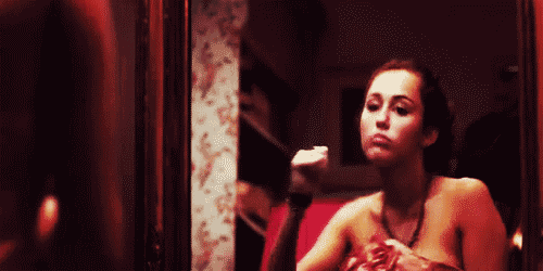 A gif of Miley Cyrus dancing in a mirror