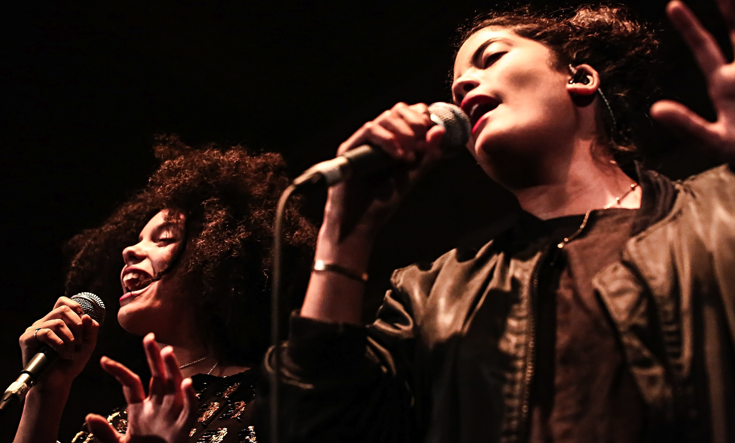 Two women singing into a microphone