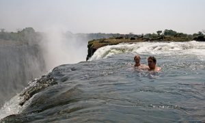 An image of a man and a woman swimming high up in a waterfall