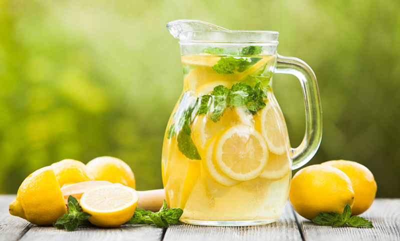 An image of lemons and a pitcher of lemonade on a table